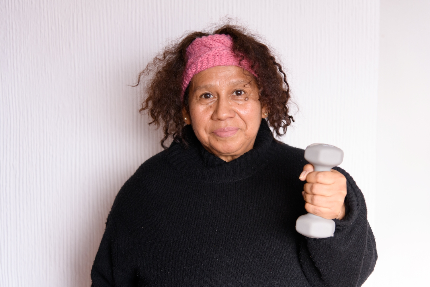 Older Latina holding hand weight